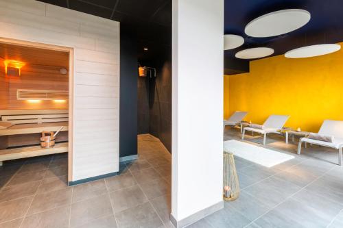 a lobby with white chairs and a yellow wall at Best Western Plus Hotel & Restaurant Les Humanistes Colmar Nord in Sélestat