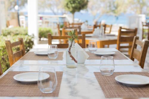 a table with plates and glasses and a vase at Akti Kastraki Beach in Kastraki Naxou