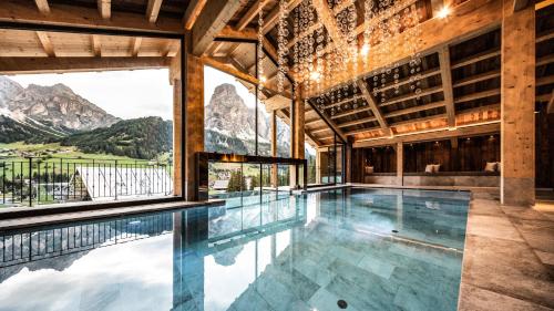 a swimming pool in a building with a mountain view at Hotel Arkadia - "Adults Only" in Corvara in Badia