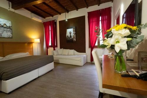 Un dormitorio con una cama y una mesa con un jarrón de flores en Alkimia Smart Rooms, en Ferrara