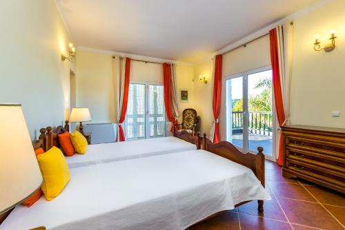een slaapkamer met twee bedden en een balkon bij Villa Amarela in Boliqueime