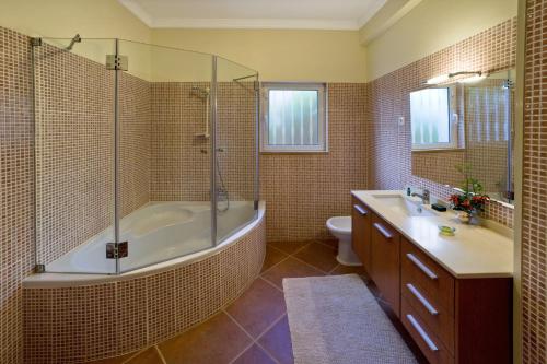 een badkamer met bad, douche en toilet bij Villa Amarela in Boliqueime