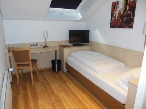a small bedroom with a bed and a desk with a computer at Hotel & Restaurant Zum Ochsen -Ox Distillery in Hösbach