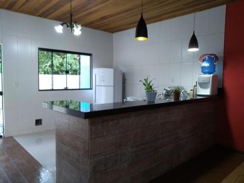 a kitchen with a counter with a refrigerator and a microwave at Chácara Recanto dos Pássaros in São Thomé das Letras