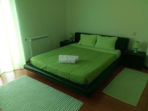 a bedroom with a green bed with two rugs at House Victoria in Nazaré
