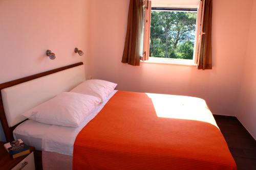 ein Schlafzimmer mit einem Bett mit einer orangefarbenen Decke und einem Fenster in der Unterkunft Gorgonia Suites in Verunic in Verunić