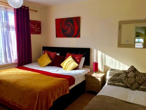 - une chambre avec un lit doté d'oreillers rouges et jaunes dans l'établissement London Luxury Apartment, Private Bathroom, à Ilford
