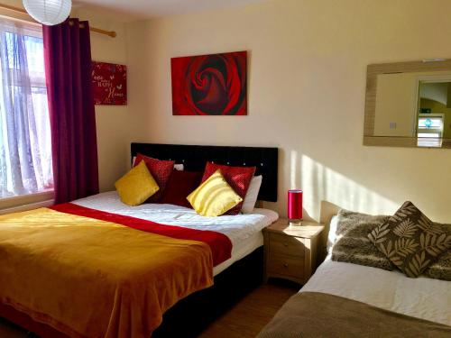 a bedroom with a bed with red and yellow pillows at Studio Apartment, Private Bathroom and Parking in Ilford