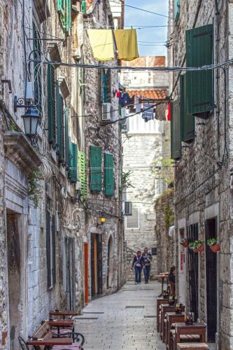 un gruppo di persone sedute su delle panchine in un vicolo di Golden Palace a Spalato (Split)