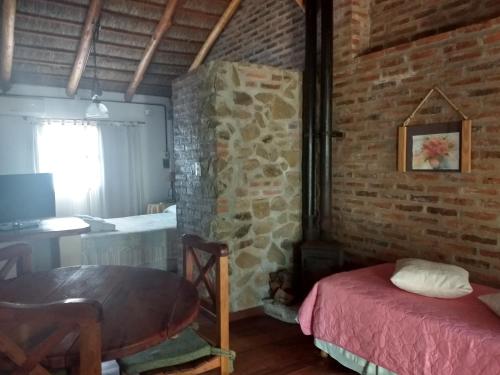 Habitación con pared de ladrillo, mesa y cama en Cabañas del Uru en Colón