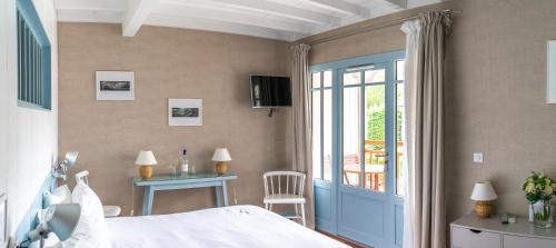 a bedroom with a bed and a table and a balcony at La Frégate in Cap-Ferret