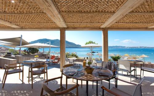a patio with tables and chairs and a view of the ocean at La Plage Casadelmar in Porto-Vecchio