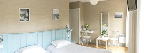 a bedroom with a bed and a table and a chair at La Frégate in Cap-Ferret