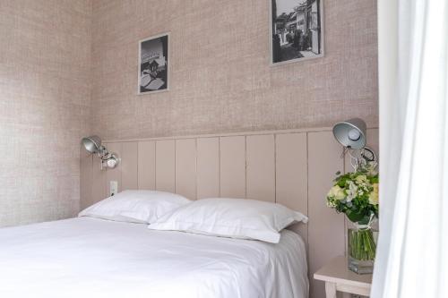 a bedroom with a white bed with two lamps and flowers at La Frégate in Cap-Ferret