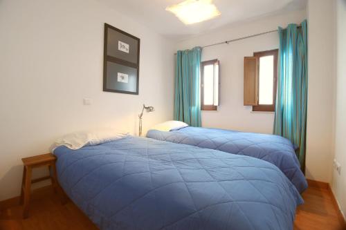 タヴィラにあるTavira Downtown Calm Houseの青いカーテン付きの客室で、青いベッド2台が備わります。