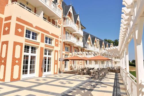un patio de un edificio con mesas y sillas en B’O Resort & Spa en Bagnoles de l'Orne
