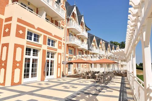 un patio de un edificio con mesas y sillas en B’O Resort & Spa, en Bagnoles de l'Orne