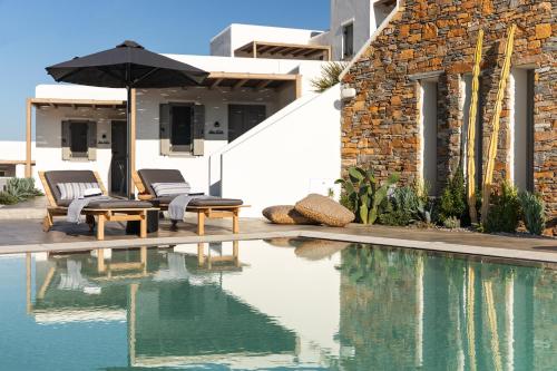 a swimming pool with two chairs and an umbrella at Chora Kythnos Suites adults only in Kithnos