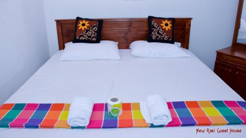 łóżko z dwoma ręcznikami na kolorowym kocu w obiekcie New Rasi Guest House w mieście Dambulla