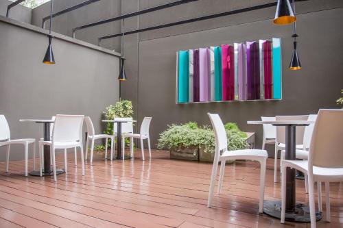 a room with tables and white chairs and a wall with books at The Point Casa Edificio Boutique in San Miguel de Tucumán