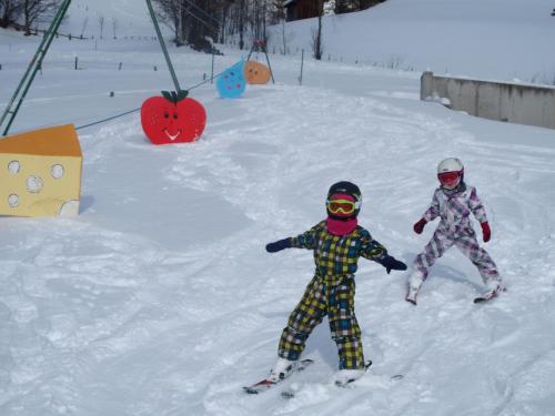 two children are skiing down a snow covered slope at Dorfergut in Weisspriach