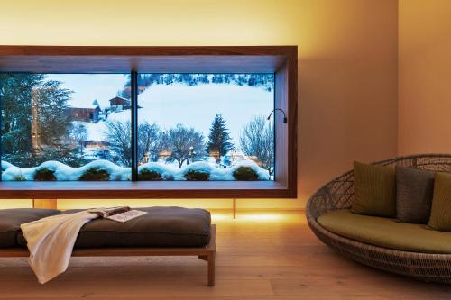 a living room with a large window with a winter view at Natürlich Hell. Aparthotel & Camping in Fügen