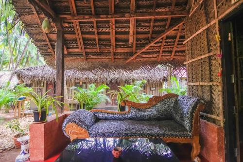 a couch sitting in a room with plants at Palm Trees Ayurvedic Heritage in Patnem