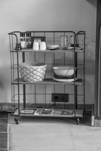 a metal shelf with plates and bowls on it at Boutique Logement Londen Centrum Middelburg in Middelburg