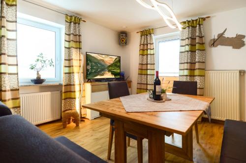a living room with a table and a tv at Apartmenthaus Vergissmeinnicht in Abtenau