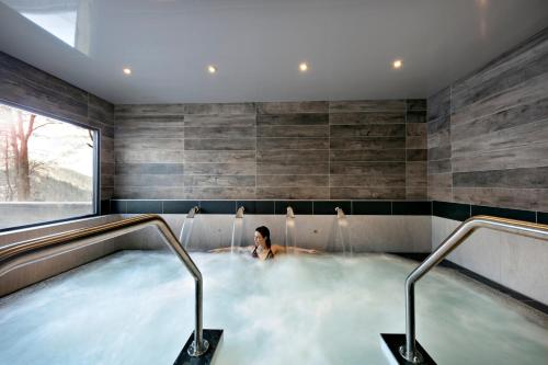 a man in a hot tub in a house at MGM Hôtels & Résidences - Résidence Chalets Elena in Les Houches