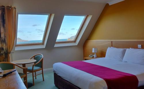 a hotel room with a bed and two windows at Hotel Ceann Sibeal in Dingle