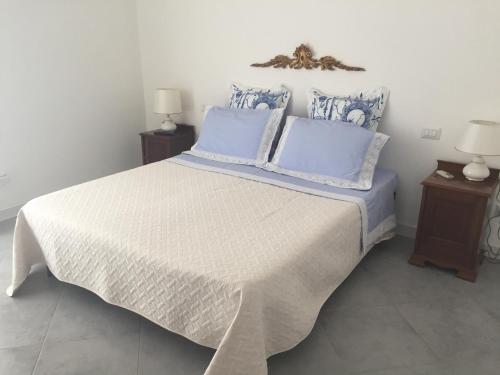 a bedroom with a white bed with blue pillows at Nel Sole di Daniel in San Felice Circeo