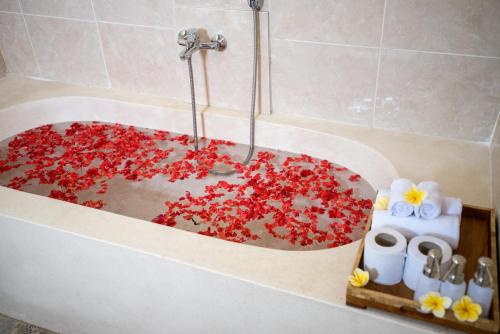 a bath tub filled with red flowers in a bathroom at Uma Jala Villa Ubud in Ubud