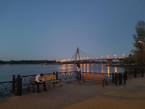 a man sitting on a bench in front of a bridge at Dream Town Apartment in Kyiv