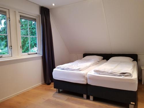 een klein bed in een kamer met 2 ramen bij Salland Vakantie in Heeten