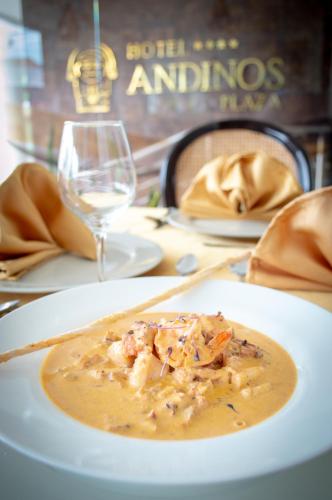 a plate of food on a table with a glass of wine at Hotel Andinos Plaza Florencia in Florencia