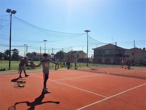 a group of people playing tennis on a tennis court at Loano 2 Village in Loano