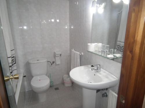 Baño blanco con aseo y lavamanos en Hostal La Muralla, en Morella