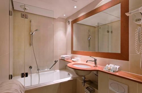 a bathroom with a sink and a tub and a mirror at Hôtel Paris Louvre Opéra in Paris