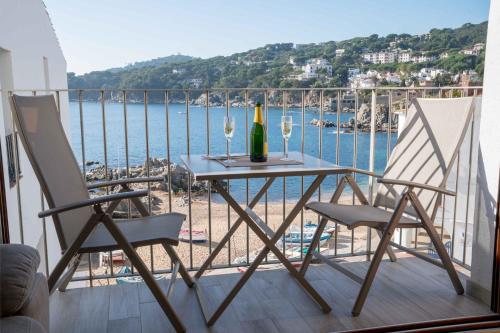 a table with two chairs and a bottle of wine on a balcony at Apartament Cortey in Calella de Palafrugell