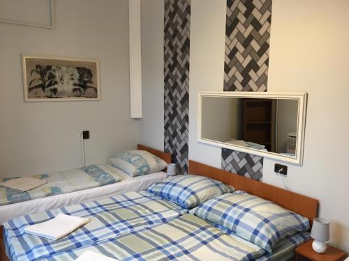 two beds in a hotel room with a mirror at Stella Vend&eacute;gh&aacute;z in Debrecen