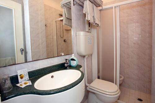 bagno con lavandino, servizi igienici e specchio di Hotel Vannini a Rimini