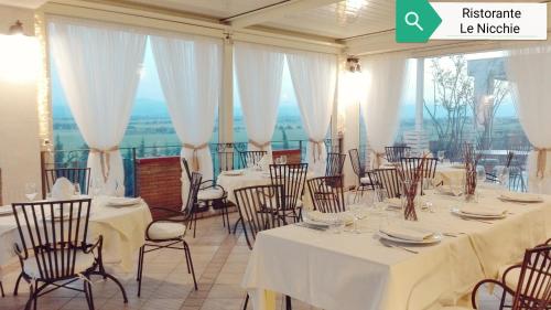 FLOS Guest House في لوتشرا: غرفة مع طاولات وكراسي مع مفارش بيضاء