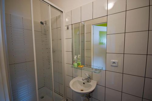 een wit betegelde badkamer met een wastafel en een douche bij Iskra in Augustów