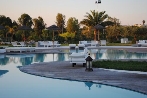 a person sitting on a bench in front of a pool of water at Hotel Borgo Pantano in Syracuse