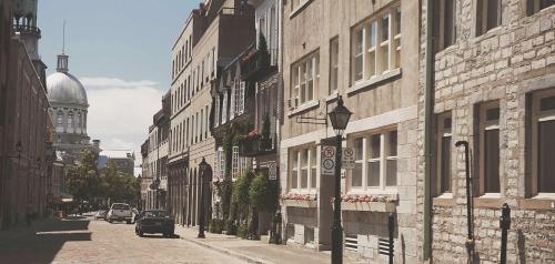 a car driving down a street next to buildings at Lofts du Vieux-Port by Gray Collection in Montréal