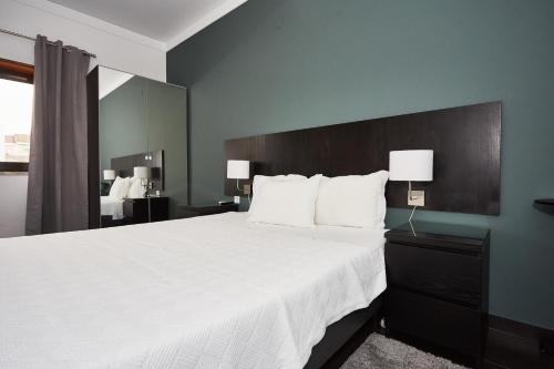 a bedroom with a large white bed and a mirror at Residencial Principe Guest House in Barreiro