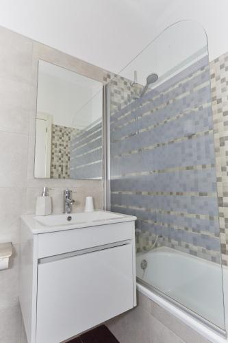 a bathroom with a sink and a tub and a mirror at Residencial Principe Guest House in Barreiro