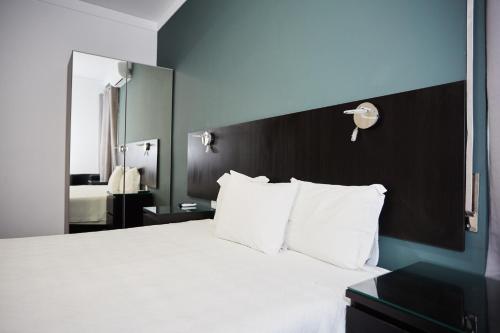 a bedroom with a large bed with white pillows at Residencial Principe Guest House in Barreiro