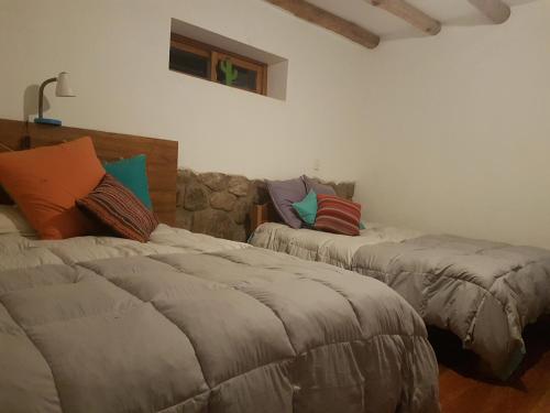 Mágico lugar en el Valle Sagrado في كوسكو: غرفة نوم بسريرين عليها مخدات